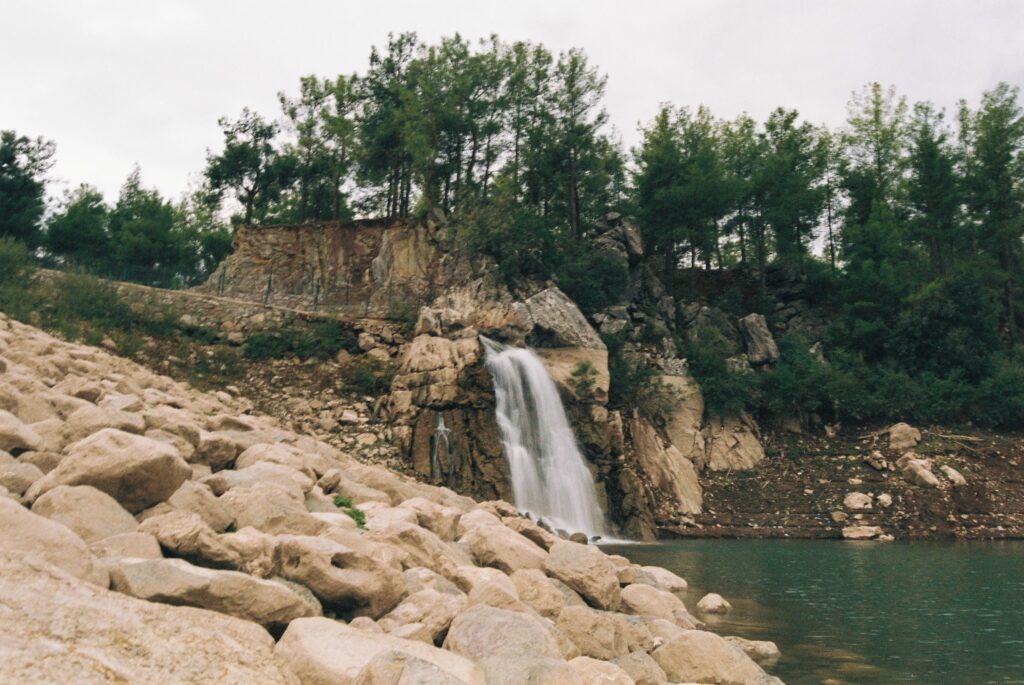 Beautiful waterfall cascading over rocks surrounded by lush greenery and trees.